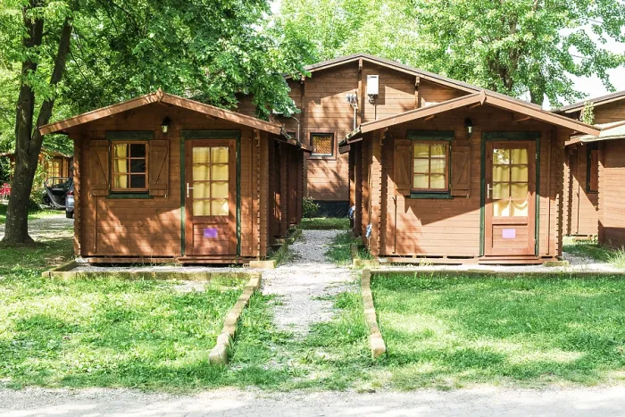 Framed Print : Wooden bungalows on campsite camping. Green trees