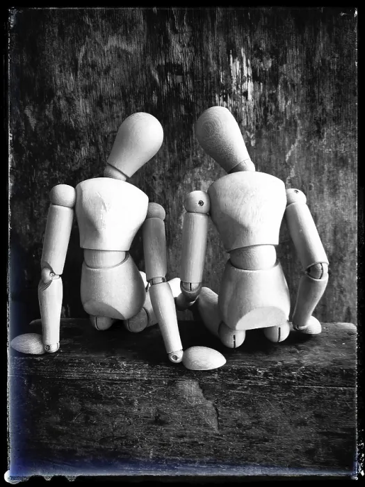 Framed Print : Two wooden figures are positioned closely together