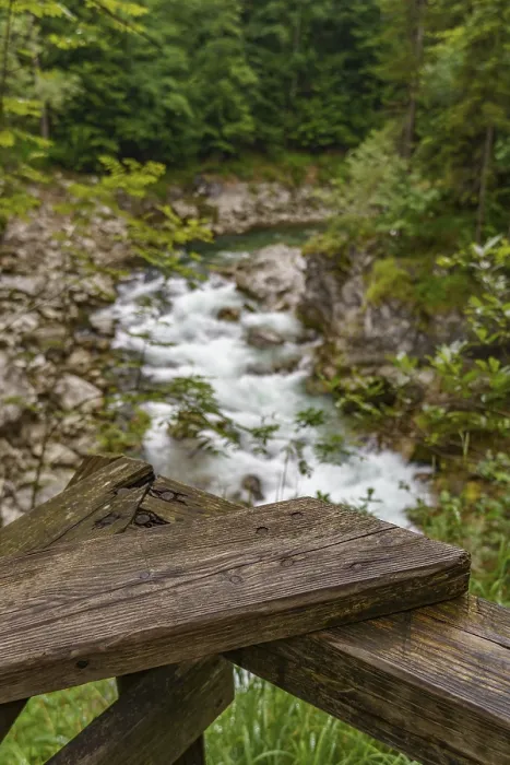 Framed Print : A wooden railing in the foreground with a view of a flowing mountain stream and rocks