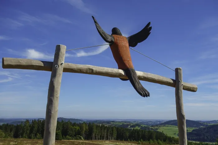 Framed Print : A wooden sculpture of a bird spreading its wings in front of a wide landscape view