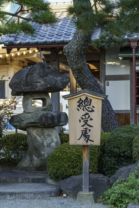 Framed Print : A wooden sign stands next to a large rock in a Japanese garden