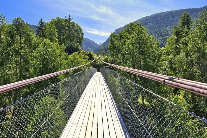Framed Print : Wooden suspension bridge in a summer landscape with mountains and lush forest Framed Print : Wooden suspension bridge in a summer landscape with mountains and lush forest
