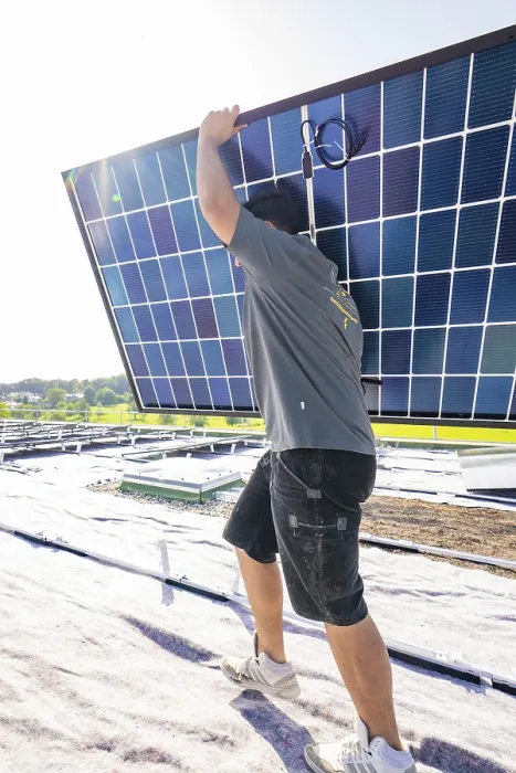 Framed Print : Worker carrying a solar panel on a roof under bright sunshine Framed Print : Worker carrying a solar panel on a roof under bright sunshine
