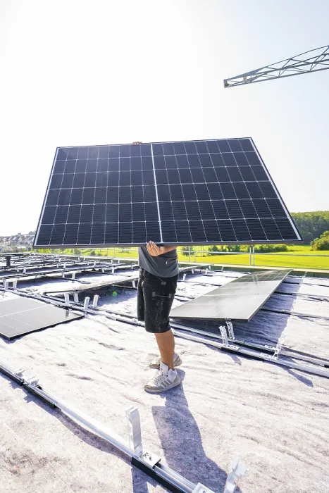 Framed Print : Worker holding a solar module on a sunny roof