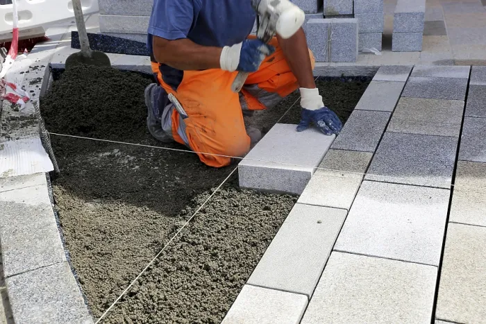 Framed Print : Worker lays paving stones