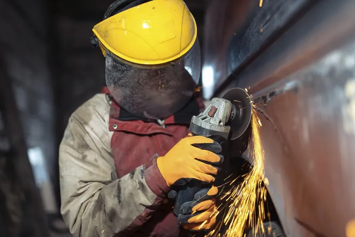 Framed Print : A worker with protective gear operates an angle grinder on a metal surface Framed Print : A worker with protective gear operates an angle grinder on a metal surface