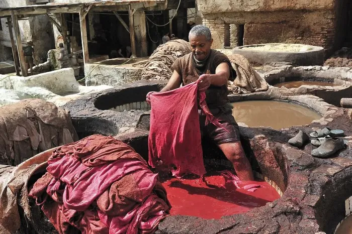 Framed Print : Worker standing in a vat of red paint to dye leather in a tannery