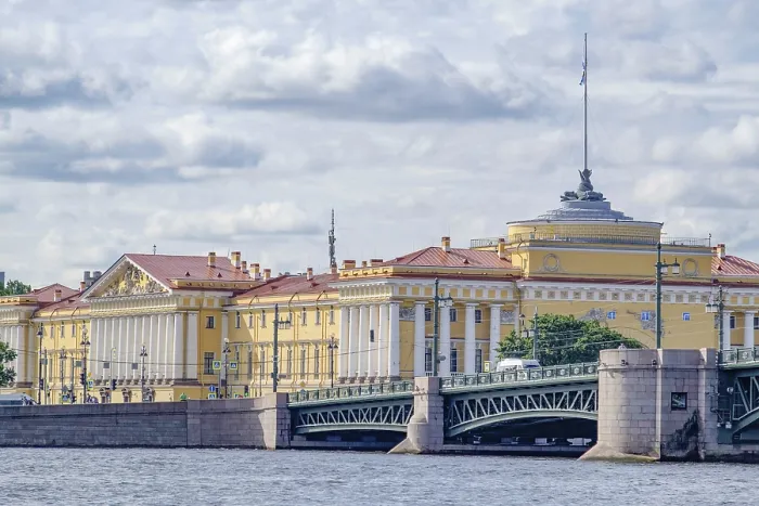 Framed Print : Yellow historic building on a river front with bridge and cloudy sky