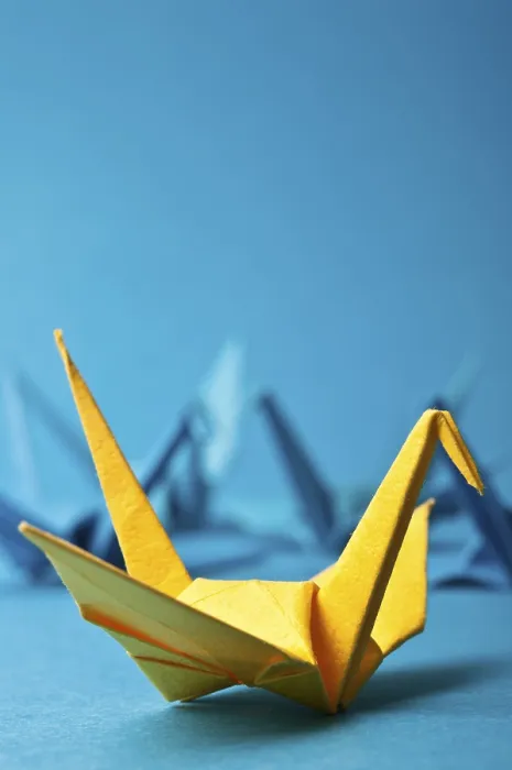 Framed Print : Yellow origami crane on a blue background with other blurry cranes