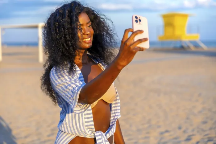 Framed Print : Young black woman taking selfie on beach using smartphone