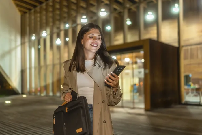 Framed Print : Young businesswoman smiling while checking her smartphone Framed Print : Young businesswoman smiling while checking her smartphone