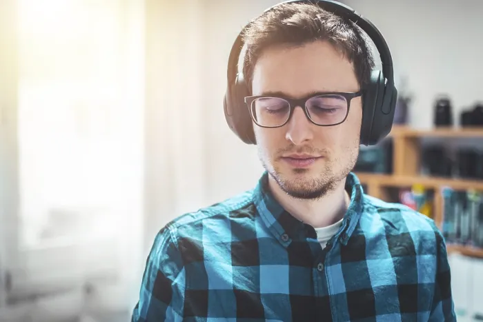 Framed Print : Young Caucasian man with checked blue shirt is listing to music with wireless headphones