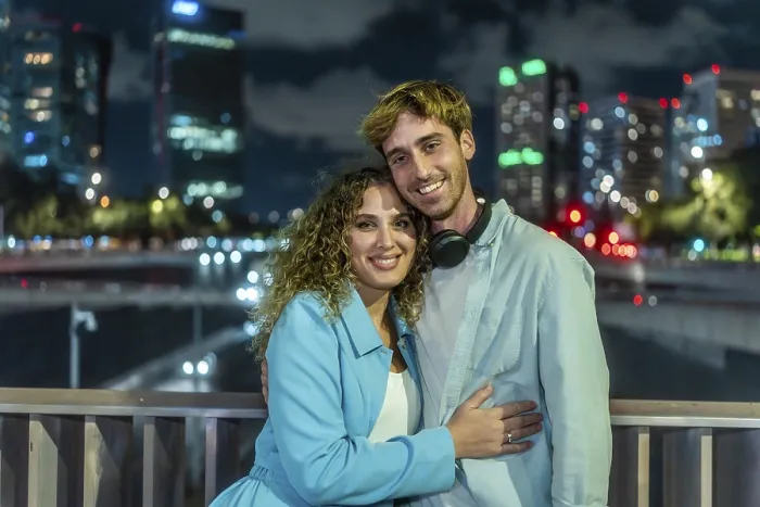 Framed Print : Young couple embracing and smiling at the camera outdoors on a bridge