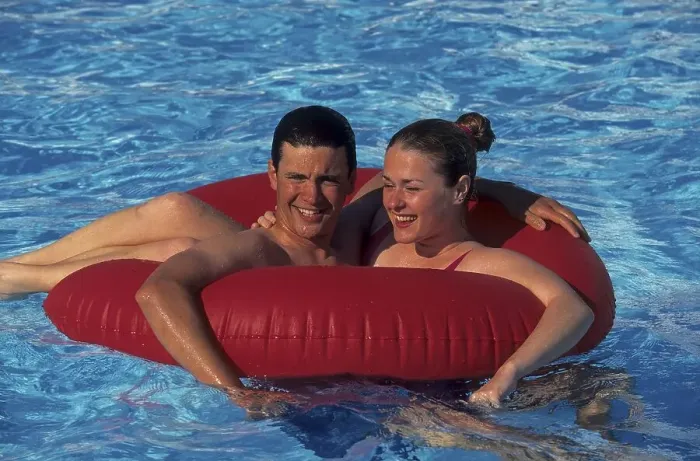 Framed Print : Young couple frolicking with red floaty tyre in swimming pool Framed Print : Young couple frolicking with red floaty tyre in swimming pool