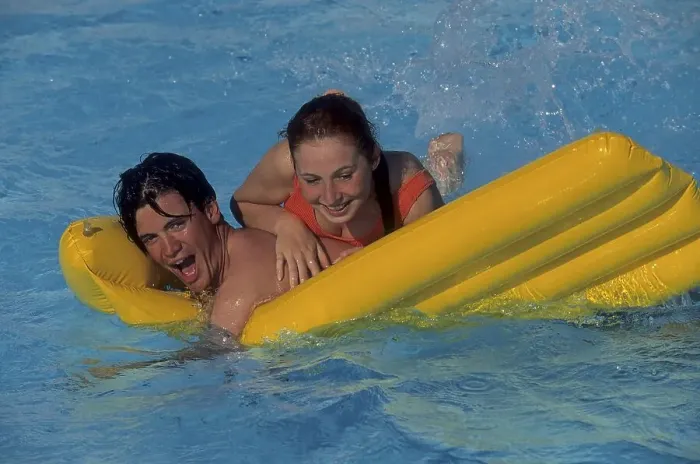 Framed Print : Young couple romps with yellow air mattress in swimming pool