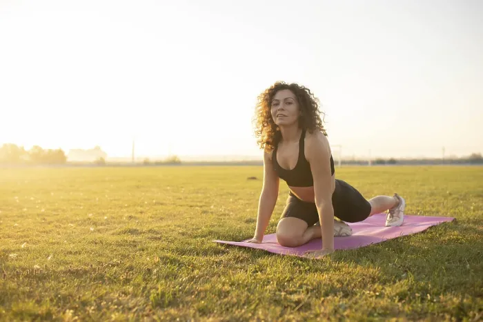 Framed Print : Young curly athletic girl in sportswear doing leg stretching on a yoga mat outdoors on the grass during sunset