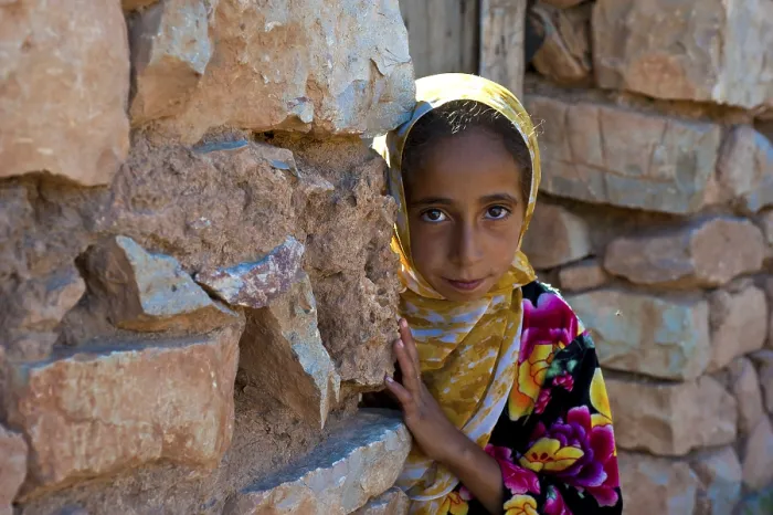 Framed Print : Young girl, berberine, looking curiously from behind a wall