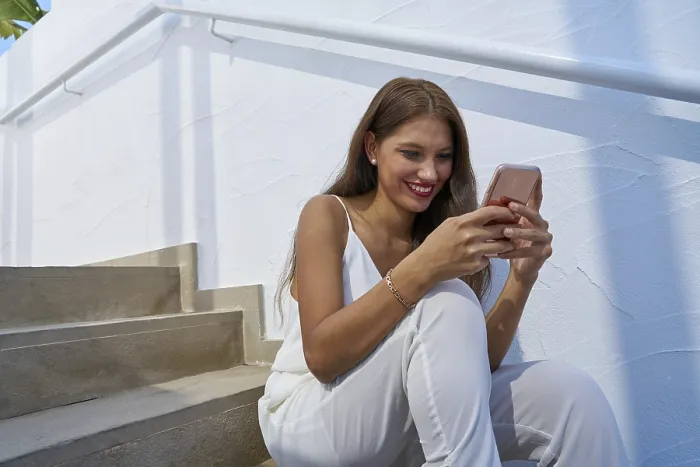 Framed Print : Young latin woman reading smarphone in a white stairway outdoor