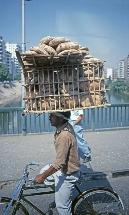 Framed Print : Young man on bicycle with bread basket on his head