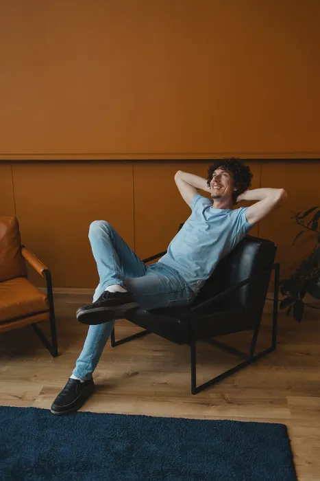 Framed Print : A young man with curly hair relaxes comfortably in a modern chair