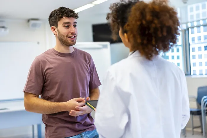 Framed Print : Young man holding a tablet, engaging in a conversation with a doctor inside a hospital room