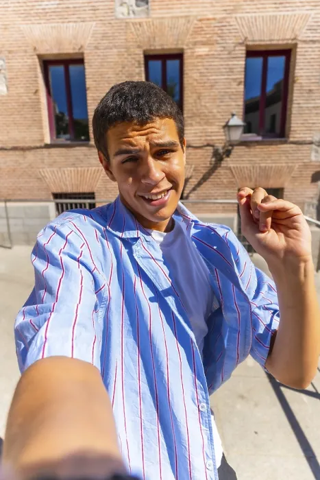 Framed Print : Young man smiling directly at the camera while taking a selfie outdoors on a sunny day
