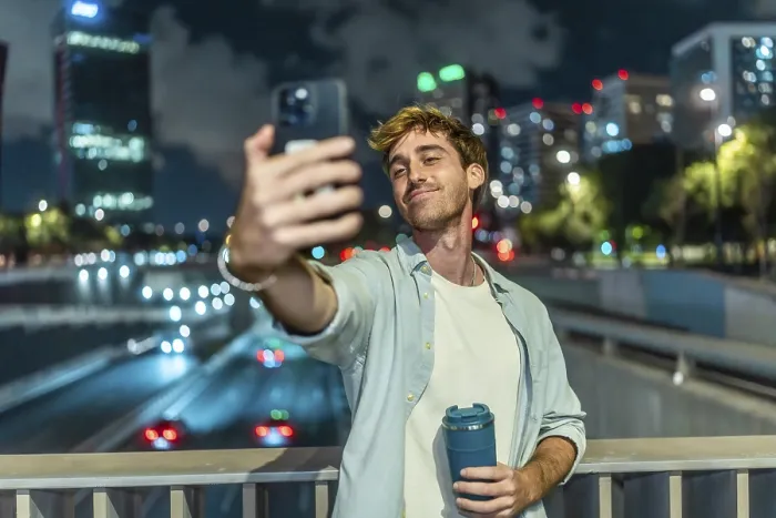 Framed Print : Young man smiling and taking a selfie with a smartphone Framed Print : Young man smiling and taking a selfie with a smartphone