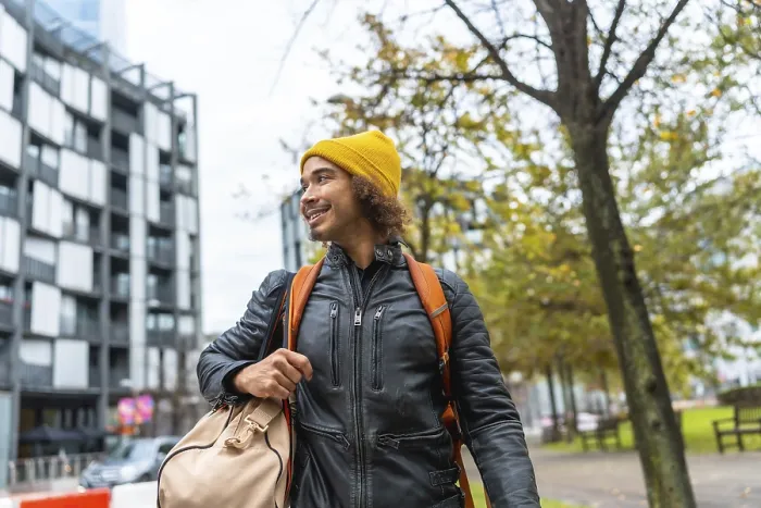 Framed Print : Young man with a yellow beanie and black leather jacket carrying a duffel bag and backpack Framed Print : Young man with a yellow beanie and black leather jacket carrying a duffel bag and backpack