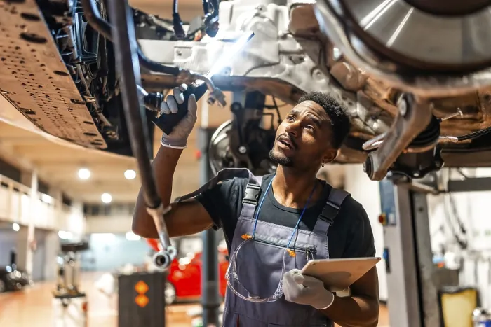 Framed Print : Young mechanic inspecting car chassis using flashlight and holding tablet in a modern workshop