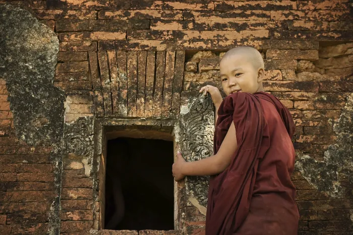Framed Print : Young novice monk standing outside Buddhist temple