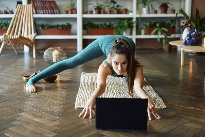 Framed Print : Young sporty woman practicing yoga at home watching online exercises on her laptop Framed Print : Young sporty woman practicing yoga at home watching online exercises on her laptop
