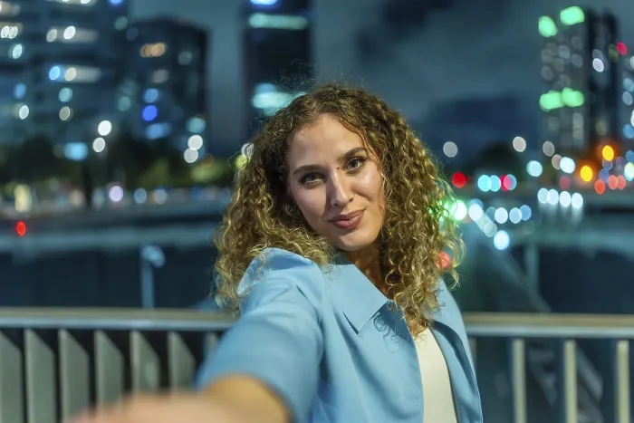 Framed Print : Young woman with curly hair extending her arm to take a selfie Framed Print : Young woman with curly hair extending her arm to take a selfie