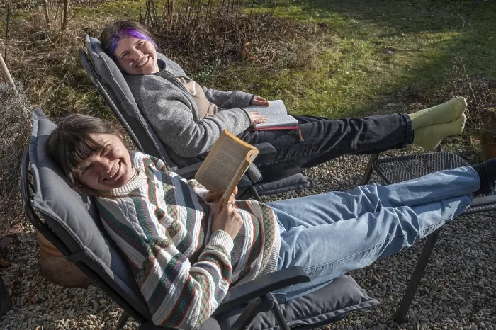Framed Print : Two young woman in a deckchair reading in the garden