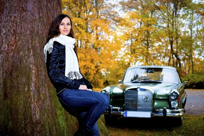 Framed Print : Young woman leaning against a tree in front of a vintage car