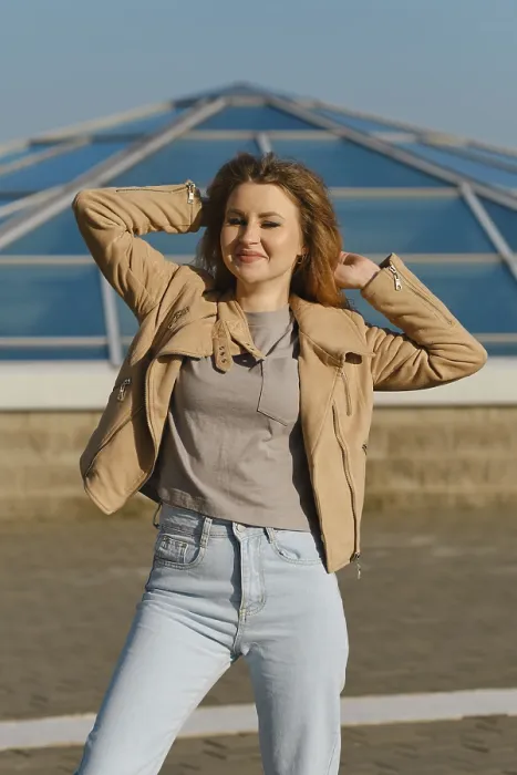 Framed Print : Young woman poses confidently in casual outfit against modern glass structure on sunny day