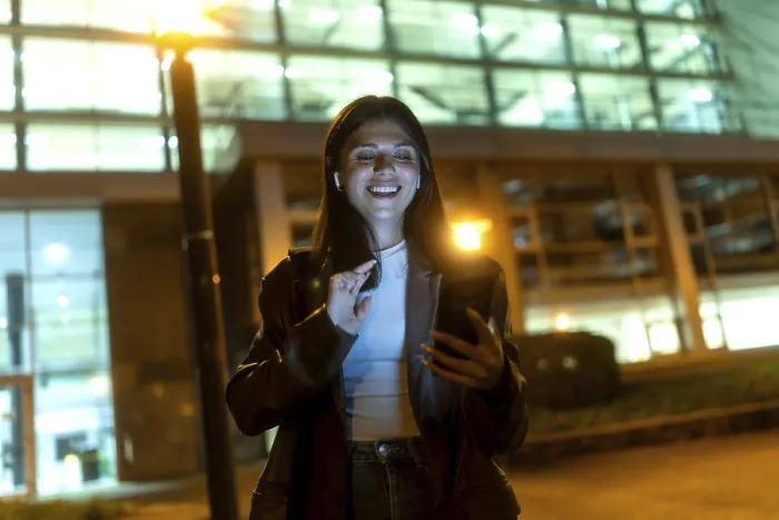 Framed Print : Young woman smiling broadly, wearing wireless earbuds and dark jacket