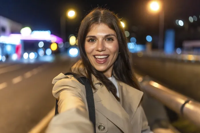 Framed Print : Young woman smiling and taking a selfie on a lively city night