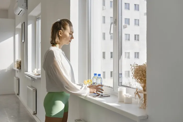 Framed Print : A young woman stands by a large window