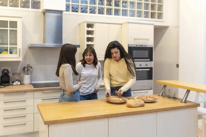 Framed Print : Three young women in a modern kitchen preparing homemade pizza