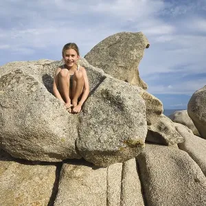 7-year-old girl climbing on the rocks at the beach of Palombaggia 7-year-old girl climbing on the rocks at the beach of Palombaggia