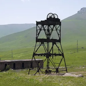 An abandoned structure in a green mountain landscape with ruined buildings and power poles