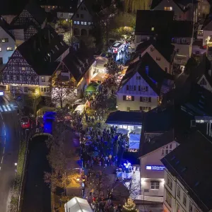 Aerial view of a Christmas market at night with a dense crowd and illuminated half-timbered houses Aerial view of a Christmas market at night with a dense crowd and illuminated half-timbered houses