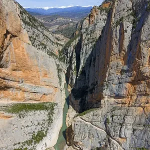 An aerial view of a narrow gorge with steep rock faces and a river flowing through the valley An aerial view of a narrow gorge with steep rock faces and a river flowing through the valley