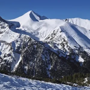 Aerial view above the Pirin mountains with rocky peaks covered with snow