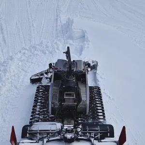 Aerial view of a snowcat working as leveling the snowdrifts on the slopes at Bansko ski resort in Bulgaria