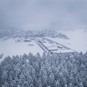 Aerial view of a snowy village surrounded by forests