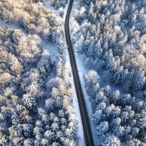 Aerial view of a snowy, winding road through a coniferous forest in winter Aerial view of a snowy, winding road through a coniferous forest in winter