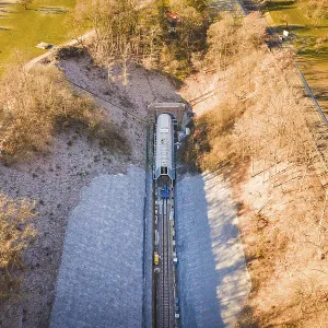 Aerial view of a train line through an autumnal forest and open meadows Aerial view of a train line through an autumnal forest and open meadows