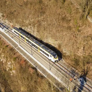 Aerial view of a train traveling through a wooded area surrounded by bare trees