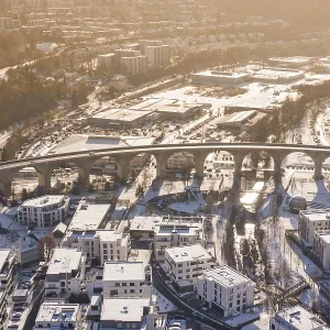Aerial view of a viaduct over a snowy town surrounded by hills in morning light